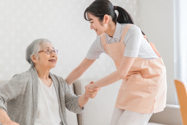 高齢女性の手を握る介護士