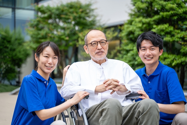 車椅子の男性と介護士の男女